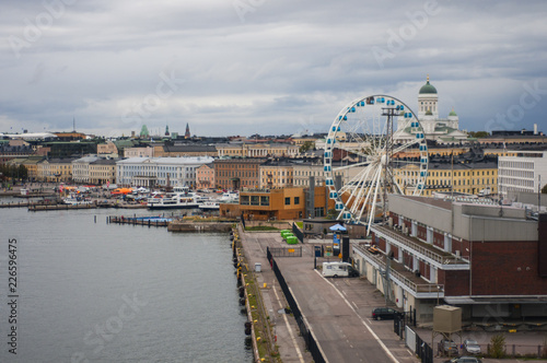 View of the city from the port. City by the sea. White temple and ferries wheel near the city port