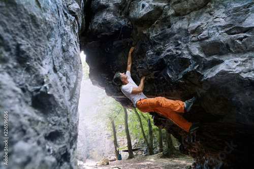 man rock climber climbing on the overhanging cliff