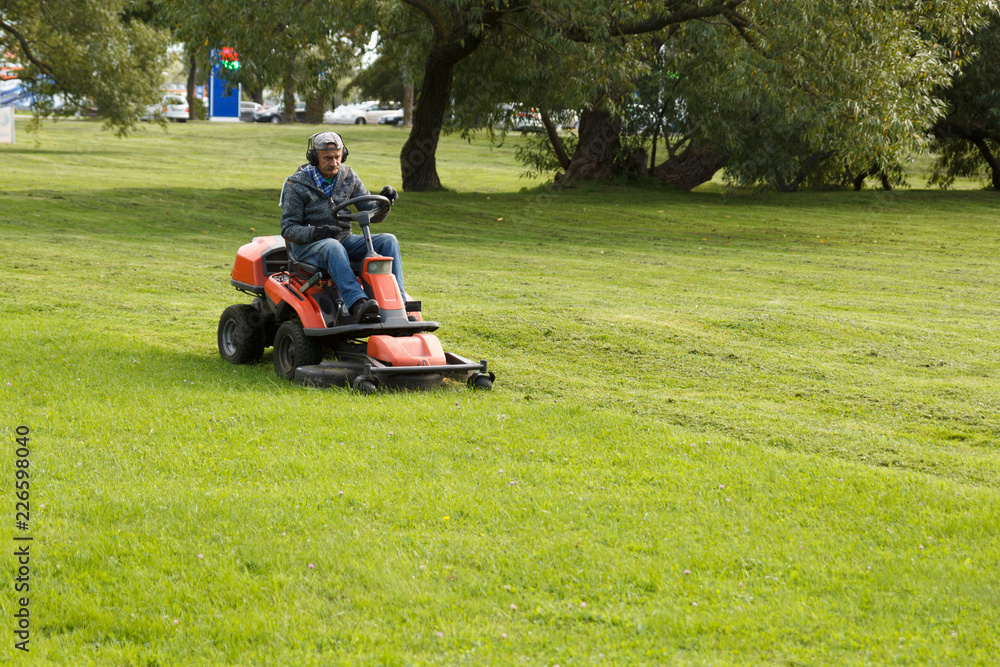 lawn mower tractor working in the town park lawn mower tractor working in the town park