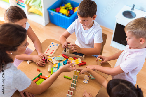 Fotografie Preschool teacher with children playing with colorful wooden didactic toys at ki