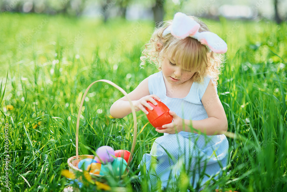 Cute funny girl with Easter eggs and bunny ears at garden. easter concept. Laughing child at Easter egg hunt