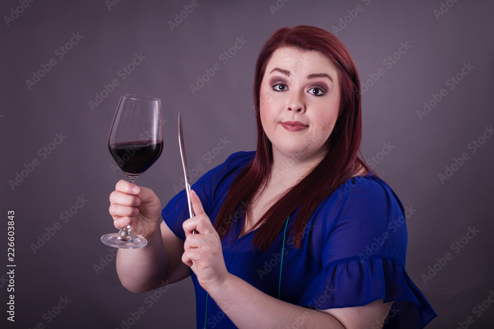 Young female clinging a glass of red wine butter knife getting attention for toast Young female clinging a glass of red wine butter knife getting attention for toast