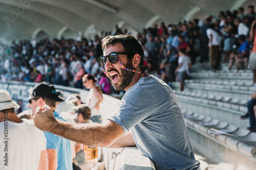 .Young man enjoying a rugby match at the stadium on a sunny autumn day. Screaming, celebrating and encouraging your team. Lifestyle.
