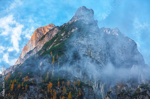 Panorama of Dachstein mountains peaks with sunset light Austria. Peaks covered with clouds photo