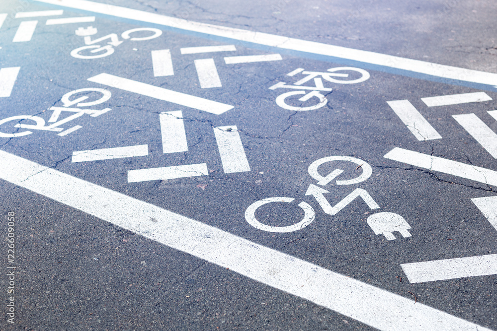 Fototapeta premium Asphalt road with bicycle and electric transport lane. Cycle and zero emission vehicles white sign on floor. Recreation area for green energy transport in city park