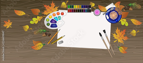Desk artist flatley. Wooden brown drawing table. On the surface of the table are paints, brushes, pencils, a palette, an eraser, as well as a cup of cappuccino on a saucer. copy space