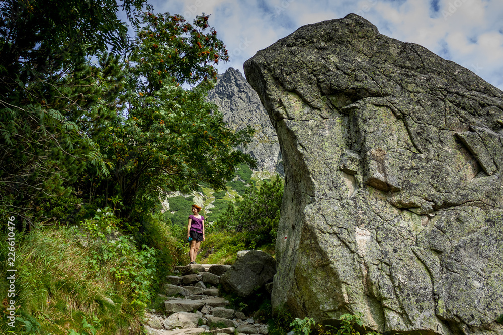 Young woman standing on path near big stone in High Tatras