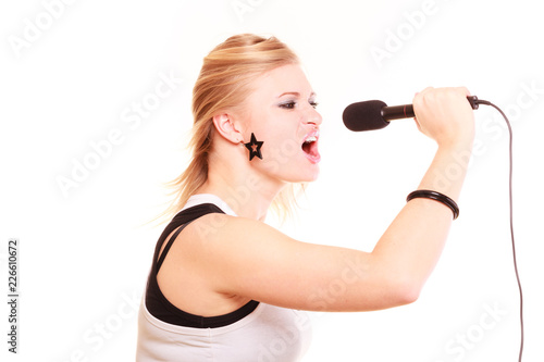 Blonde woman singing to microphone, profile view