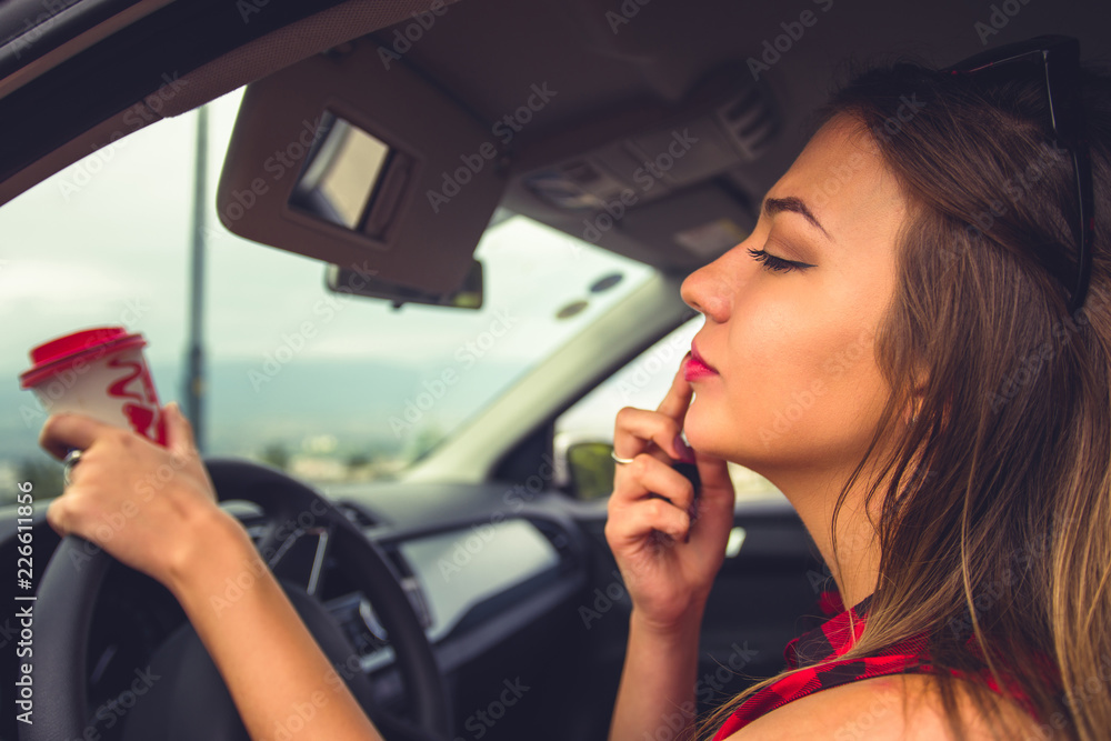 Woman fixing her lipstick in a car Woman fixing her lipstick in a car