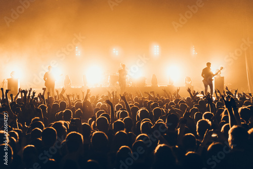 silhouettes of concert crowd in front of bright stage lights. A sold out crowd on rock concert. Crowd of fans at music festive. Party in nightclub.