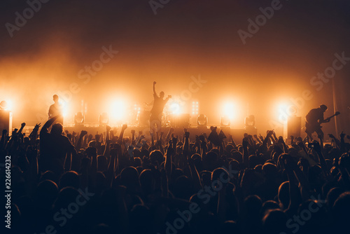 silhouettes of concert crowd in front of bright stage lights. A sold out crowd on rock concert. Crowd of fans at music festive. Party in nightclub.