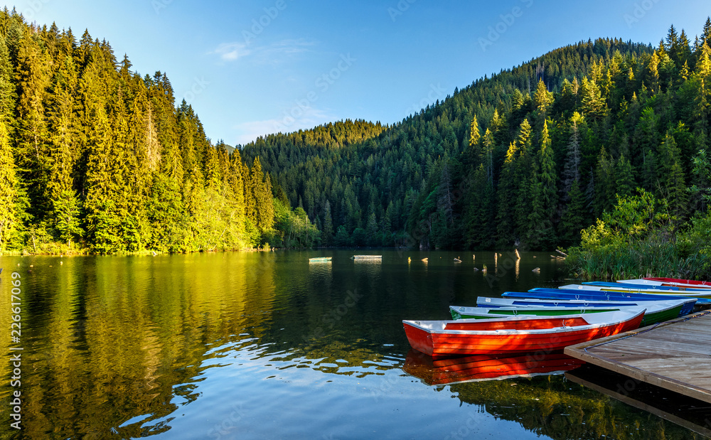 majestic mountain lake Lacul Rosu in mountain. boats under sunli majestic mountain lake Lacul Rosu in mountain. boats under sunli
