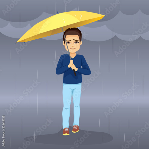 Sad hopeless man holding yellow umbrella walking on raining day with dark clouds