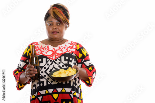 Studio shot of fat black African woman holding bottle of beer an
