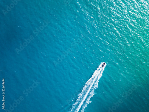 Obraz na plátne Bird's eye aerial top view of a boat cruising in crystal clear turquoise sea wat