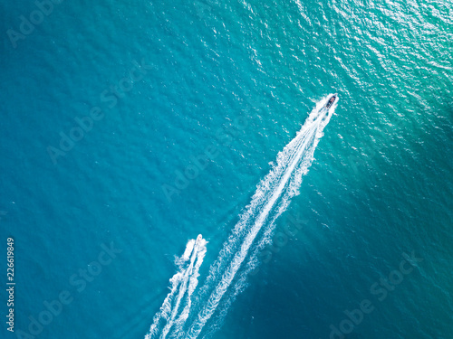 Aerial top view of two boats cruising in clear turquoise sea water