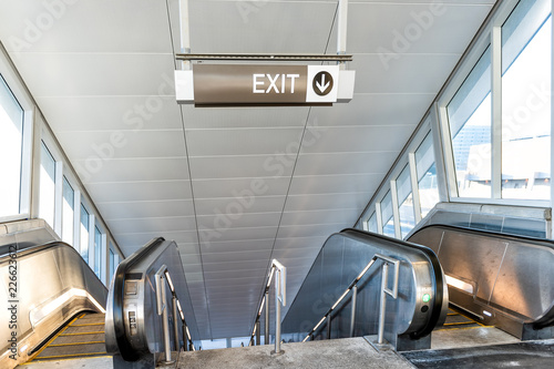 Exit sign in subway, metro station with escalators walkway going underground, windows and bright light photo