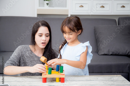 Mother and child play toy together on the living room at home, kid with developing learning for education with activity with family, mom teaching daughter with fun and skill in pastime.