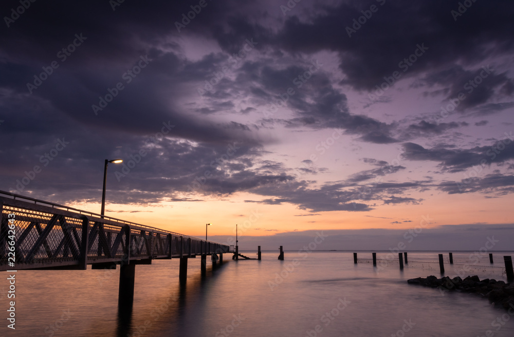 Stormy skies and beach jetty at sunset