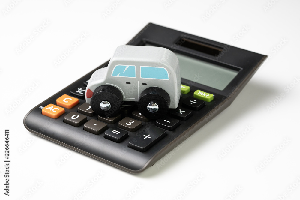 Car leasing, rental or insurance and maintenance calculation concept, cute wooden small toy car parking on black calculator on white background, down payment, installment for auto market Car leasing, rental or insurance and maintenance calculation concept, cute wooden small toy car parking on black calculator on white background, down payment, installment for auto market