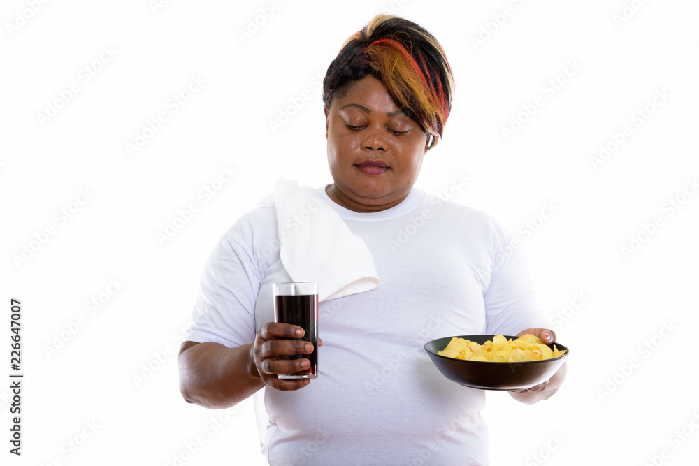 Studio shot of fat black African woman looking at glass of soda Studio shot of fat black African woman looking at glass of soda