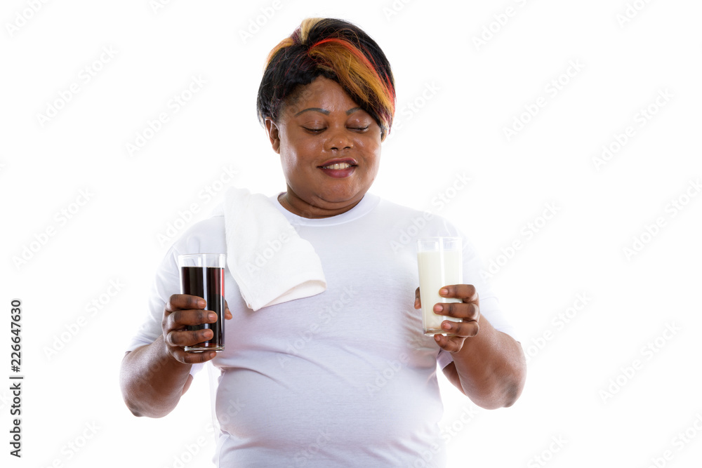 Studio shot of happy fat black African woman smiling while holdi Studio shot of happy fat black African woman smiling while holdi