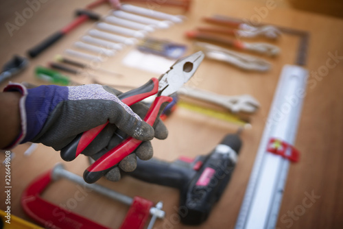 Hand holding pliers with craftsman tool background