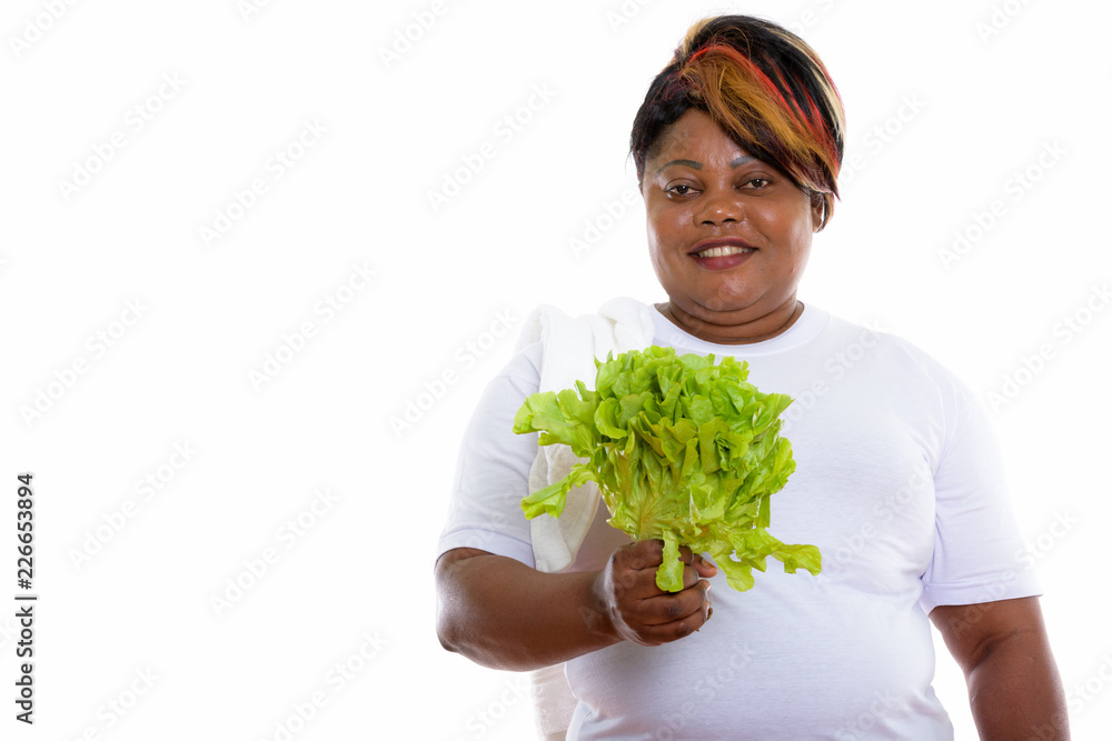 Studio shot of happy fat black African woman smiling while holdi Studio shot of happy fat black African woman smiling while holdi