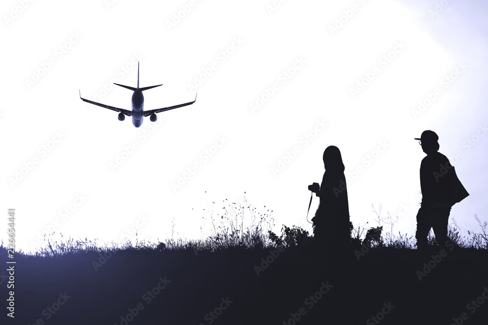 silhouette of two people on the background of a flying plane