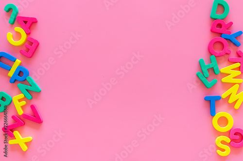 Alphabet for kids concept. English letters in disorder on pink background top view copy space