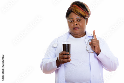 Studio shot of fat black African woman doctor holding glass of s photo