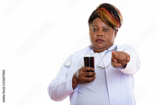 Studio shot of fat black African woman doctor holding glass of s photo