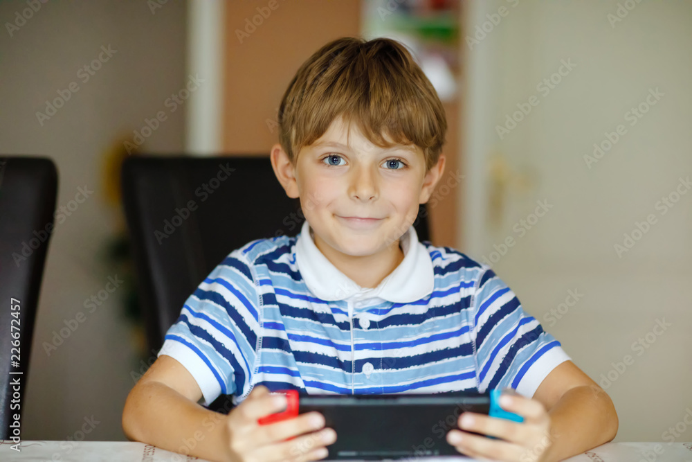 Happy little kid boy playing with game controller. Child gaming with friends at home via internet console. Happy little kid boy playing with game controller. Child gaming with friends at home via internet console.
