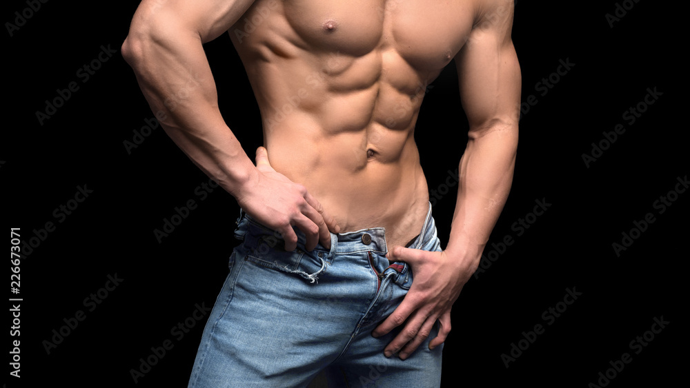 Closeup torso of shirtless muscular man posing on a black background Closeup torso of shirtless muscular man posing on a black background