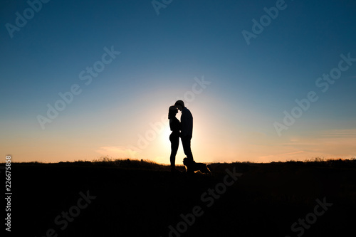 Romantic couple hug at sunset on background.