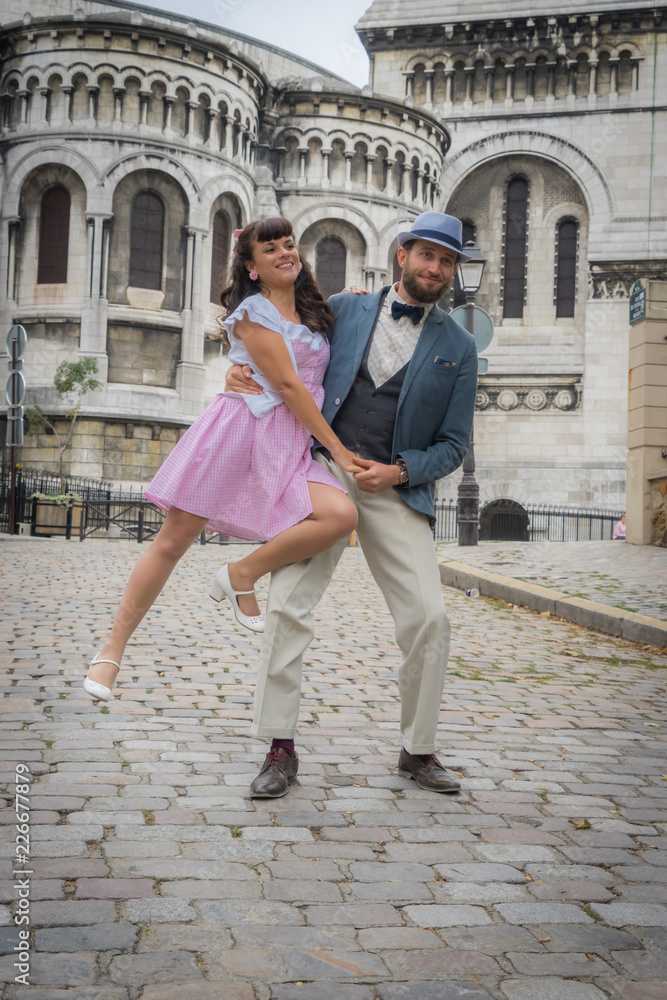 Paris, France - 10 07 2018: Montmartre. Photo shoot in Montmartre outdoor at Citadin Park. Female and male model, dancing and swinging with the Sacred Heart in the background