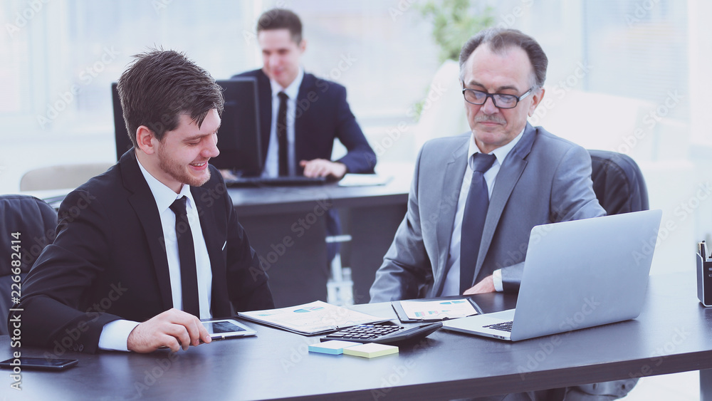 boss and employee discussing the document sitting at the Desk in the office. boss and employee discussing the document sitting at the Desk in the office.