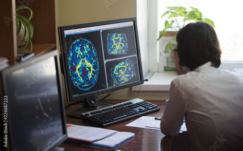 A radiologist is working on a CT scan of a brain tumor