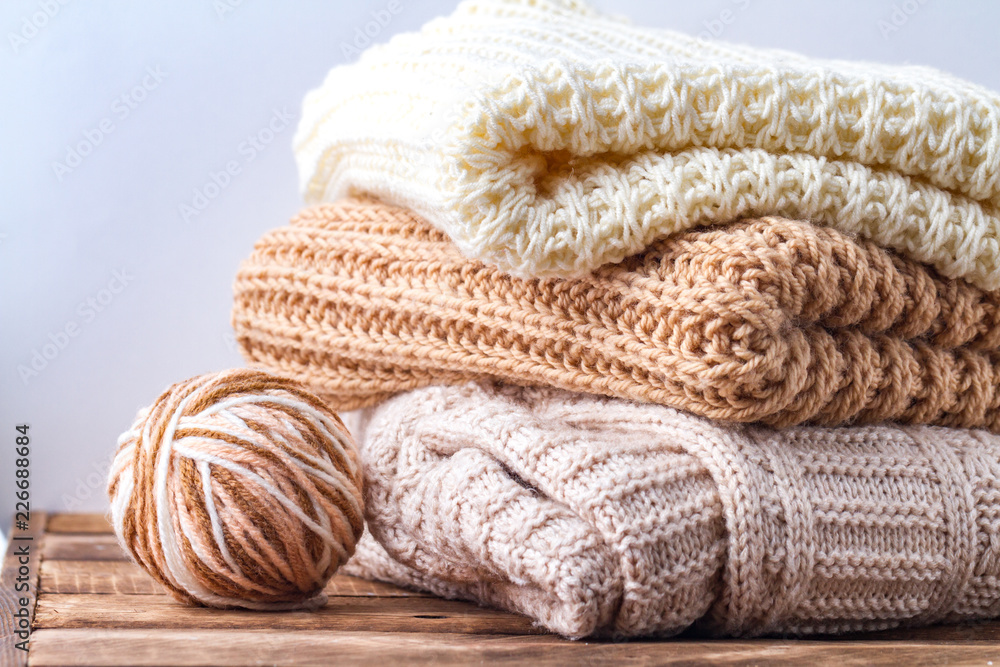 Warm, pastel clothes, knitted, pastel-colored scarves and a ball of knitting yarn on a white background. Winter, autumn clothes. Warm, pastel clothes, knitted, pastel-colored scarves and a ball of knitting yarn on a white background. Winter, autumn clothes.