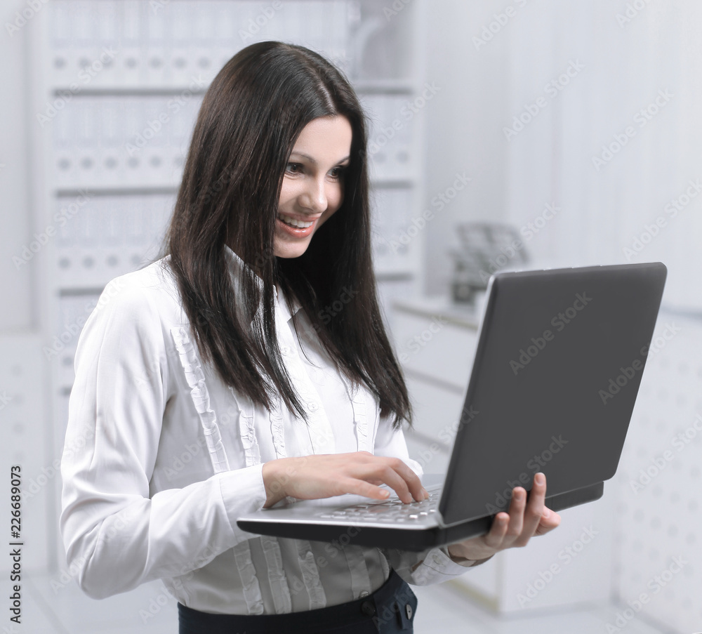 female assistant using laptop standing in office. female assistant using laptop standing in office.