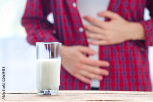 A woman feels bad, has an upset stomach, bloating due to lactose intolerance. Dairy intolerant person. Health care concept. Lactose intolerance and dairy products photo