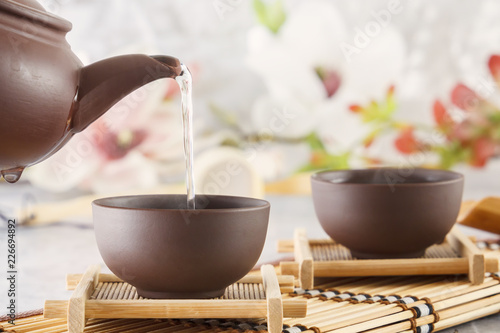 Boiling water from a ceramic kettle is poured into a traditional Chinese cup at a tea ceremony. Close-up