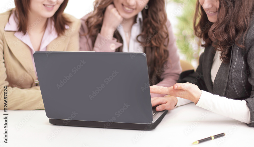 younger employees looking at laptop screen in office. younger employees looking at laptop screen in office.