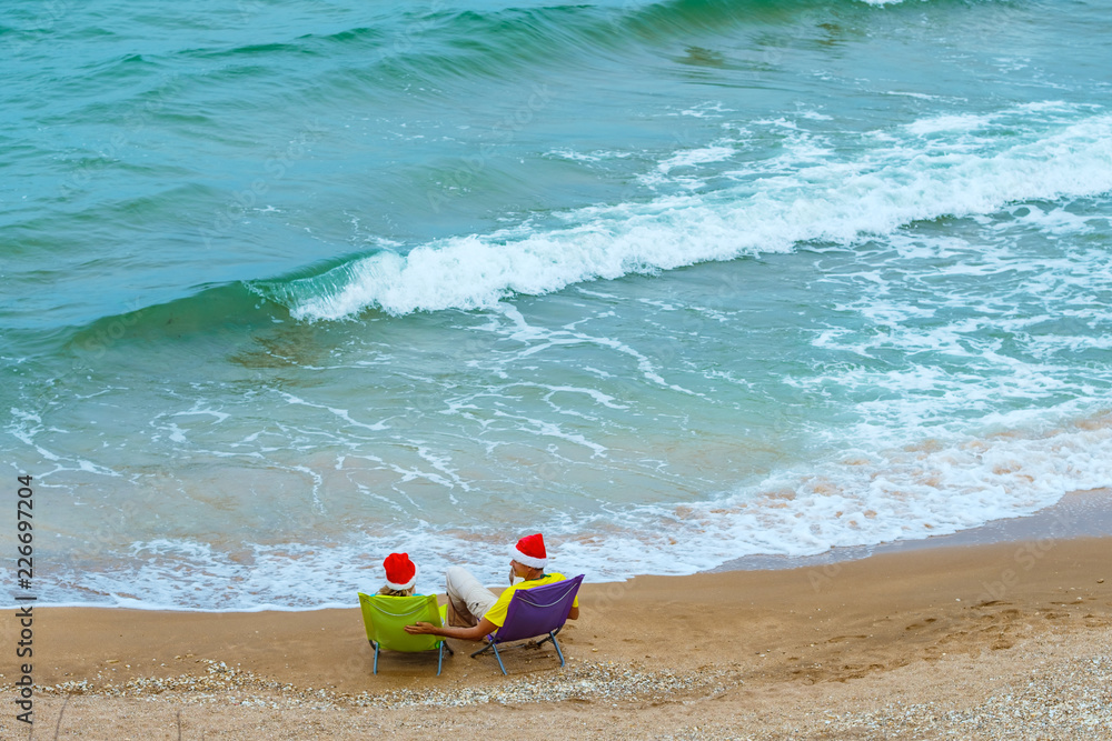 Couple Sitting On Beach Wearing Santa Hats View from above Couple Sitting On Beach Wearing Santa Hats View from above