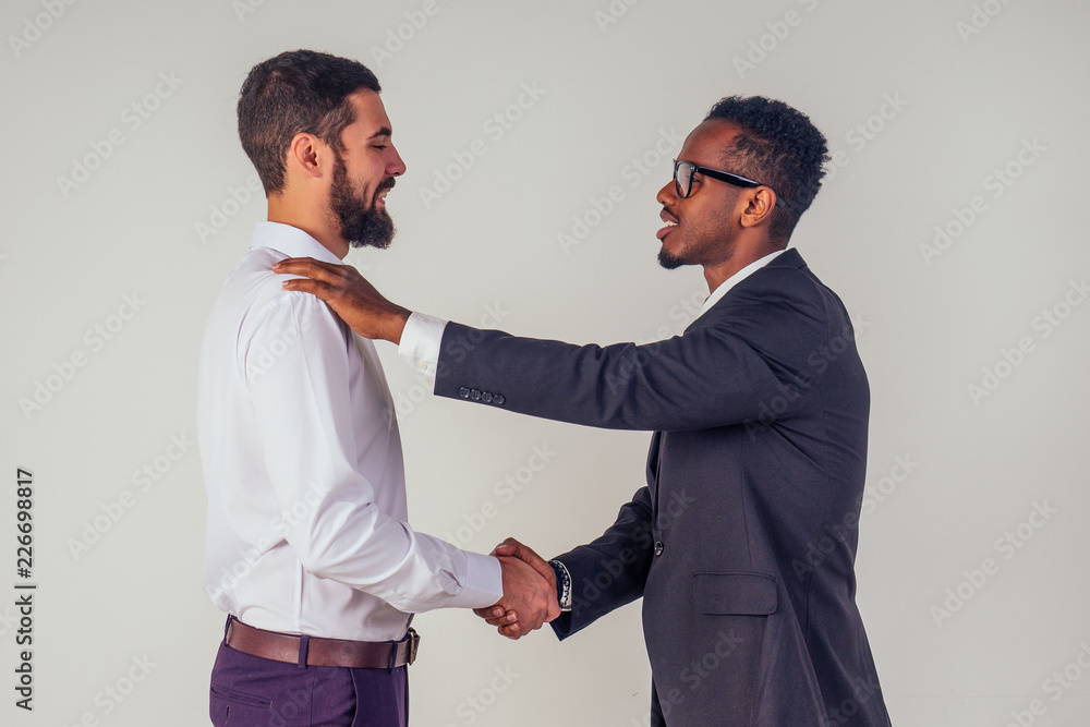 male businessman and his Aro-American partner shaking hands in the studio on a white background