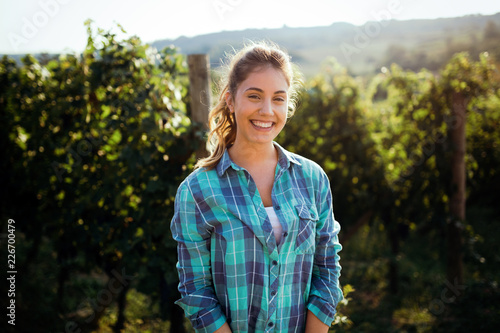 Quadro su tela Woman winemaker with grapes in a vineyard