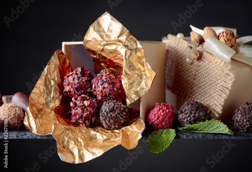 Various chocolates with mint leaves in small gift box.