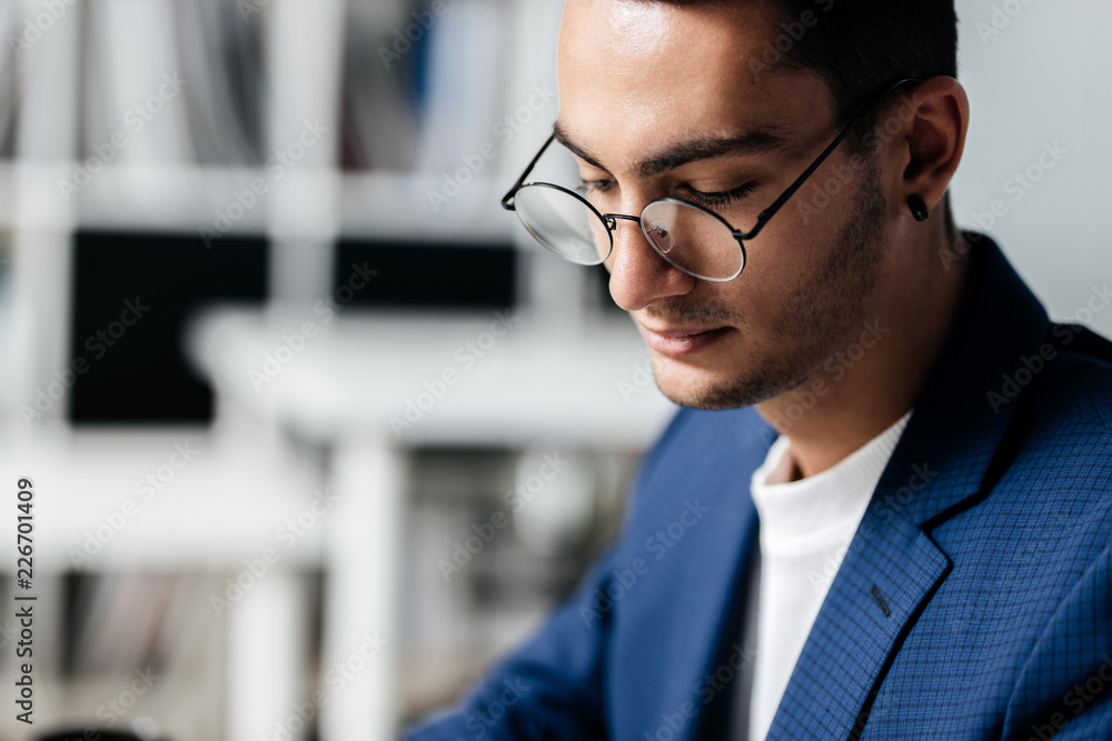 Fototapeta premium Portrait of dark-haired young architect in glasses dressed in blue checkered jacket