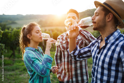 Fototapeta Wine growers tasting wine in vineyard