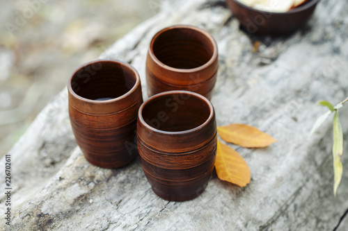 clay cups with tea on a wooden log in autumn among the leaves